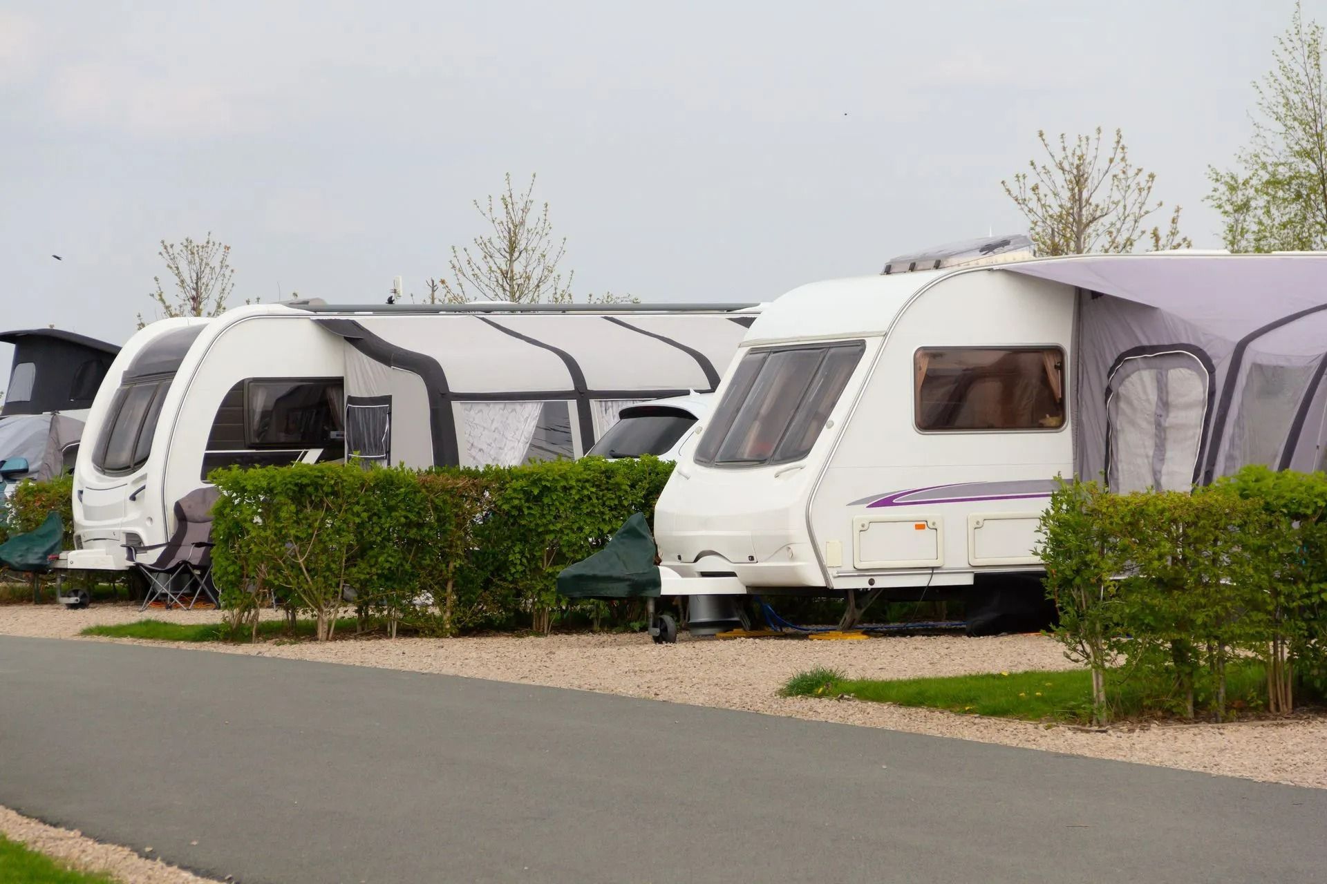 Plusieurs caravanes blanches étaient garées en rang le long de haies taillées, sur une route tranquille.