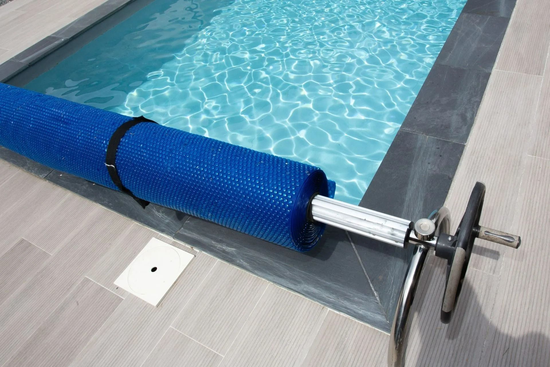 Bâche de piscine bleu foncé enroulée au bord d'une piscine