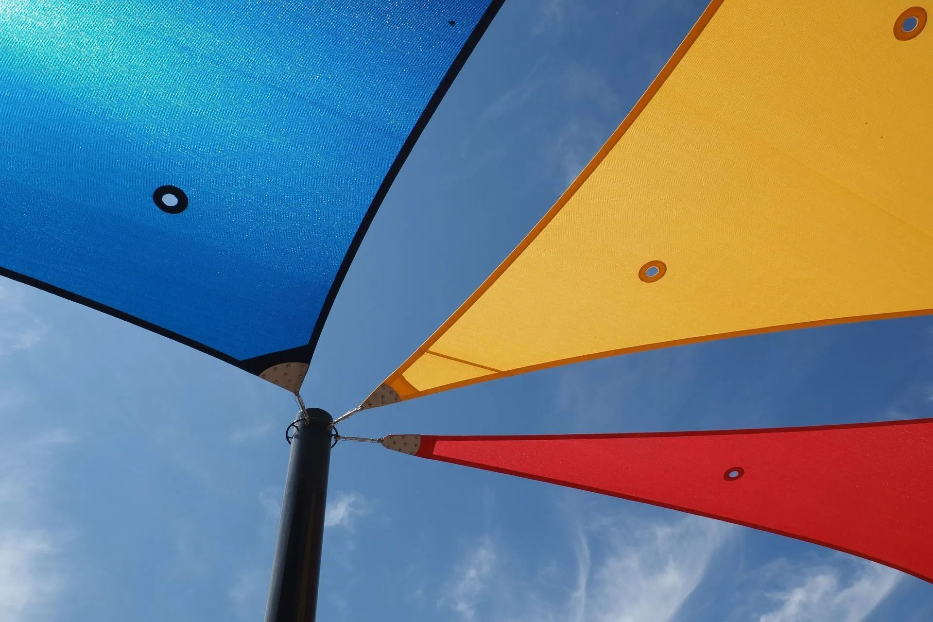 Des bâches colorées se détachant sur un ciel bleu, vus d'en bas.