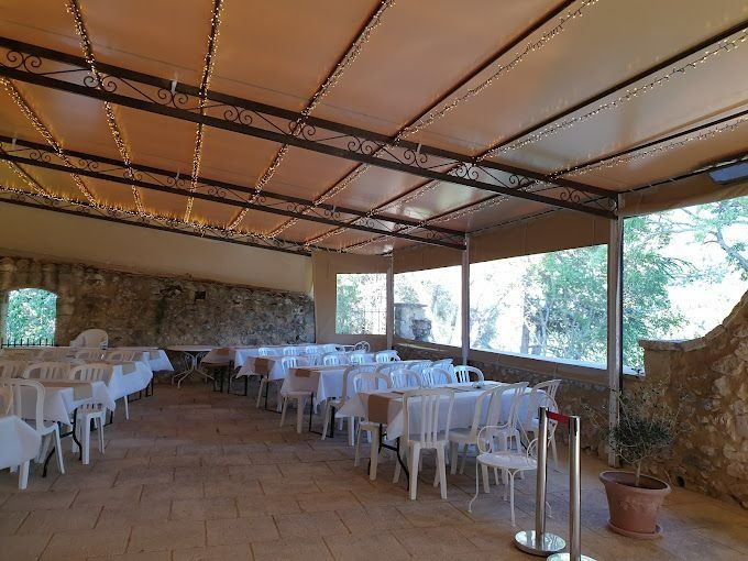 Espace repas en plein air avec tables et chaises en plastique blanc sous une terrasse couverte