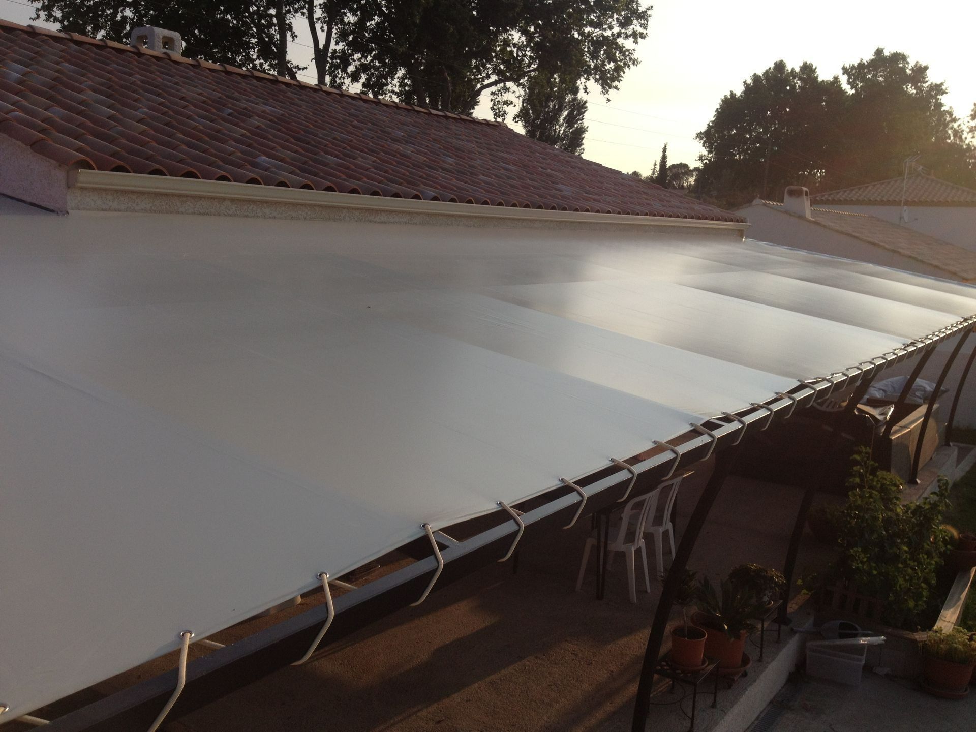 Grande bâche blanche tendue au-dessus d'un patio près d'une maison