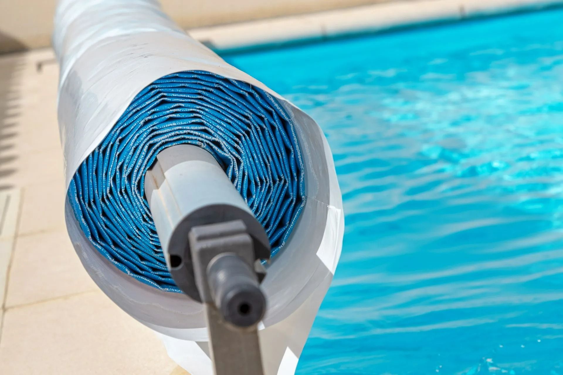 Bâche de piscine bleue enroulée sur un dévidoir sur le bord d'une piscine