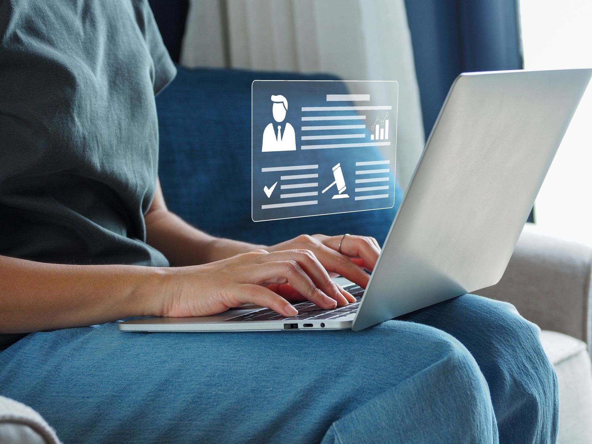 Una persona está sentada en un sofá usando una computadora portátil.