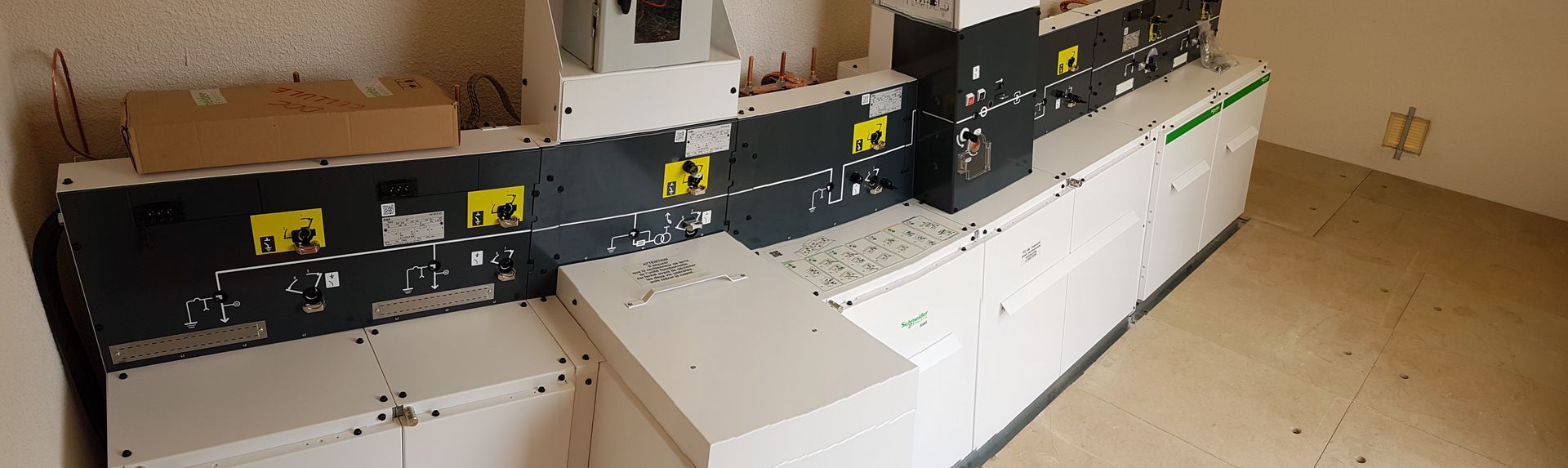 Grosse machine industrielle dans une pièce avec des composants blancs et gris et de multiples panneaux de commande.