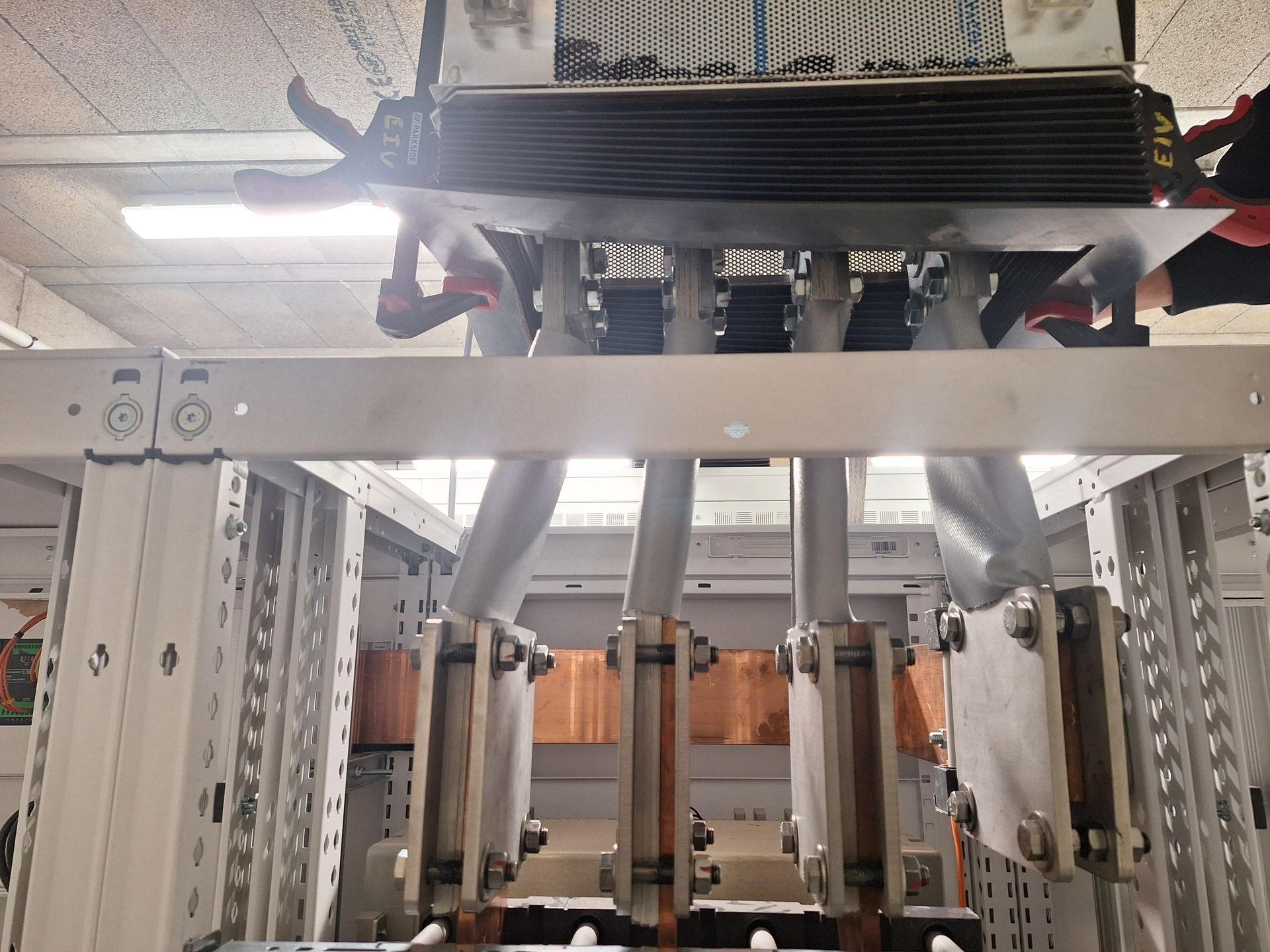 Manipulation d'un équipement électrique comportant de gros connecteurs en cuivre et un composant noir.