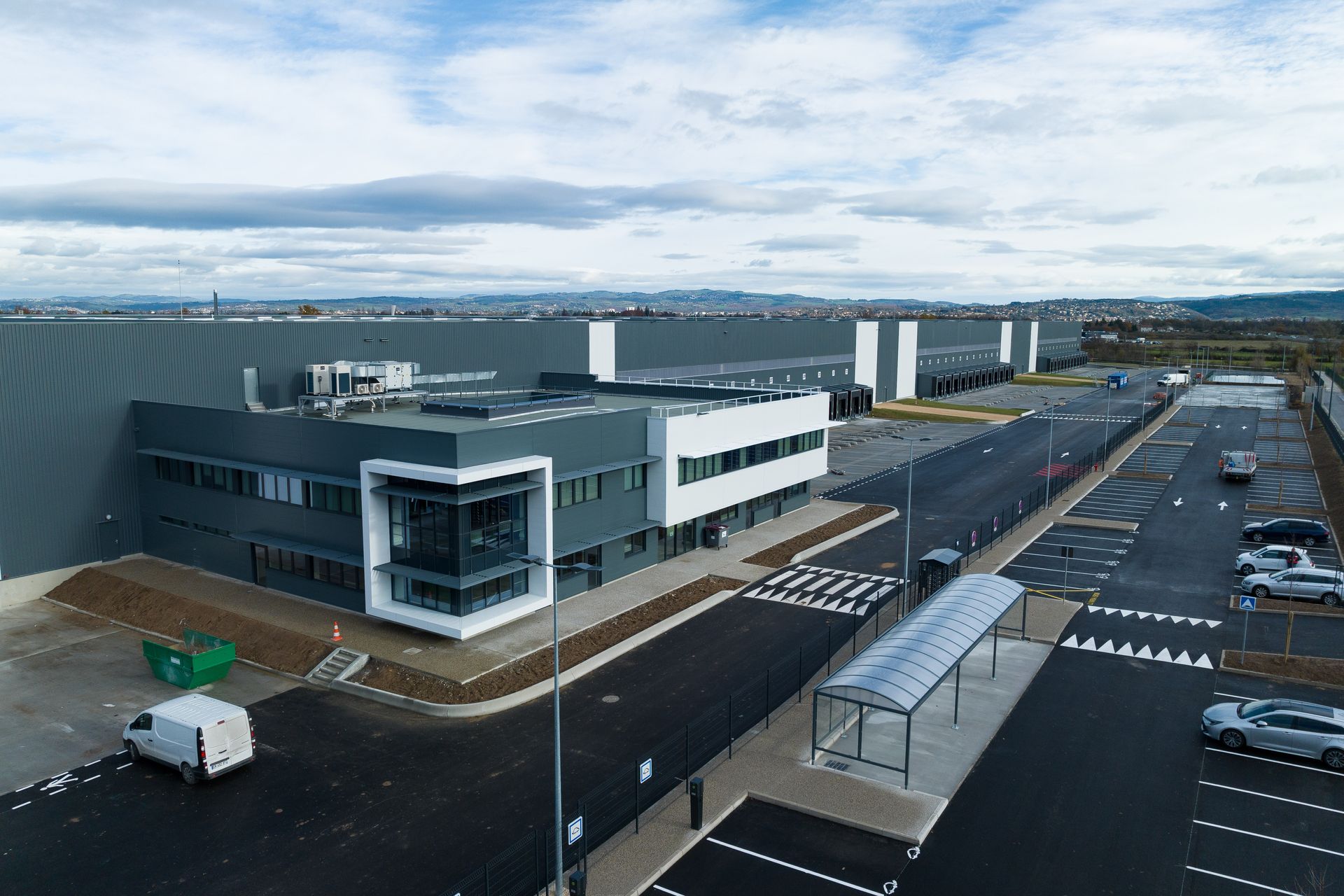 Vue extérieure d'un complexe moderne d'entrepôts et de bureaux avec parking.