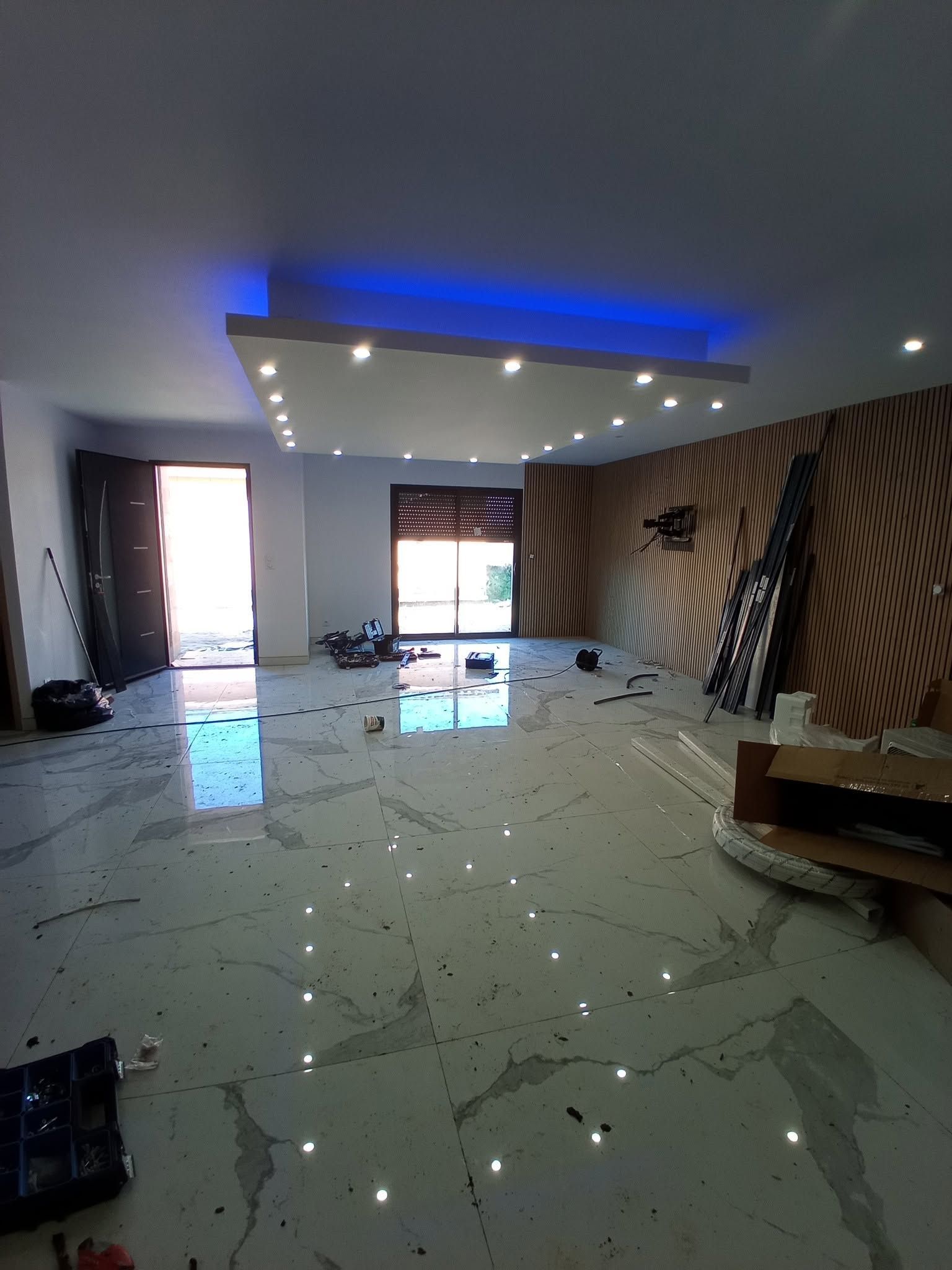 Salon moderne avec un plafond éclairé et un mur d’accent à rayures.