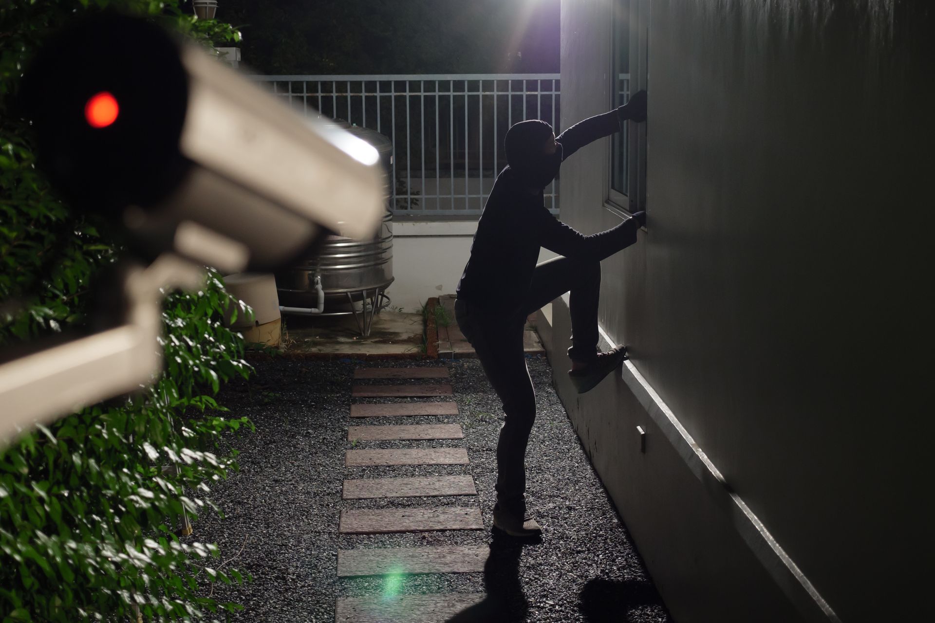 Silhouette d’une personne escaladant la façade d'une maison, filmée par une caméra de sécurité.