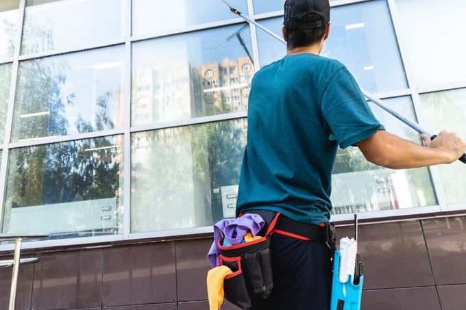 Limpiador de ventanas que utiliza una escobilla de goma sobre los cristales de las ventanas de un edificio.