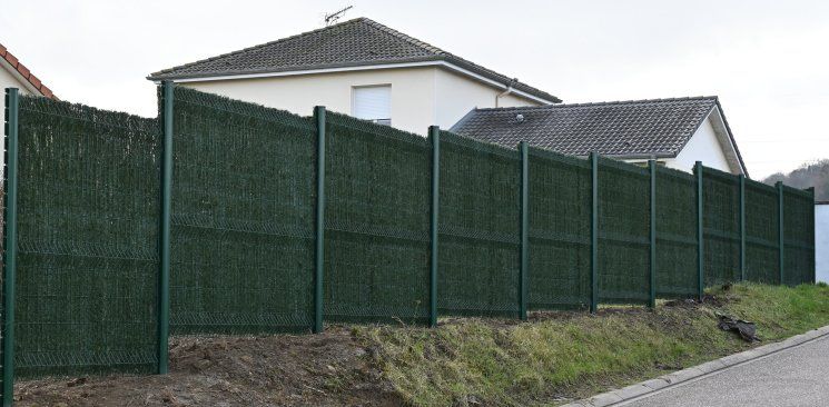 Clôture verte située à côté d'une maison