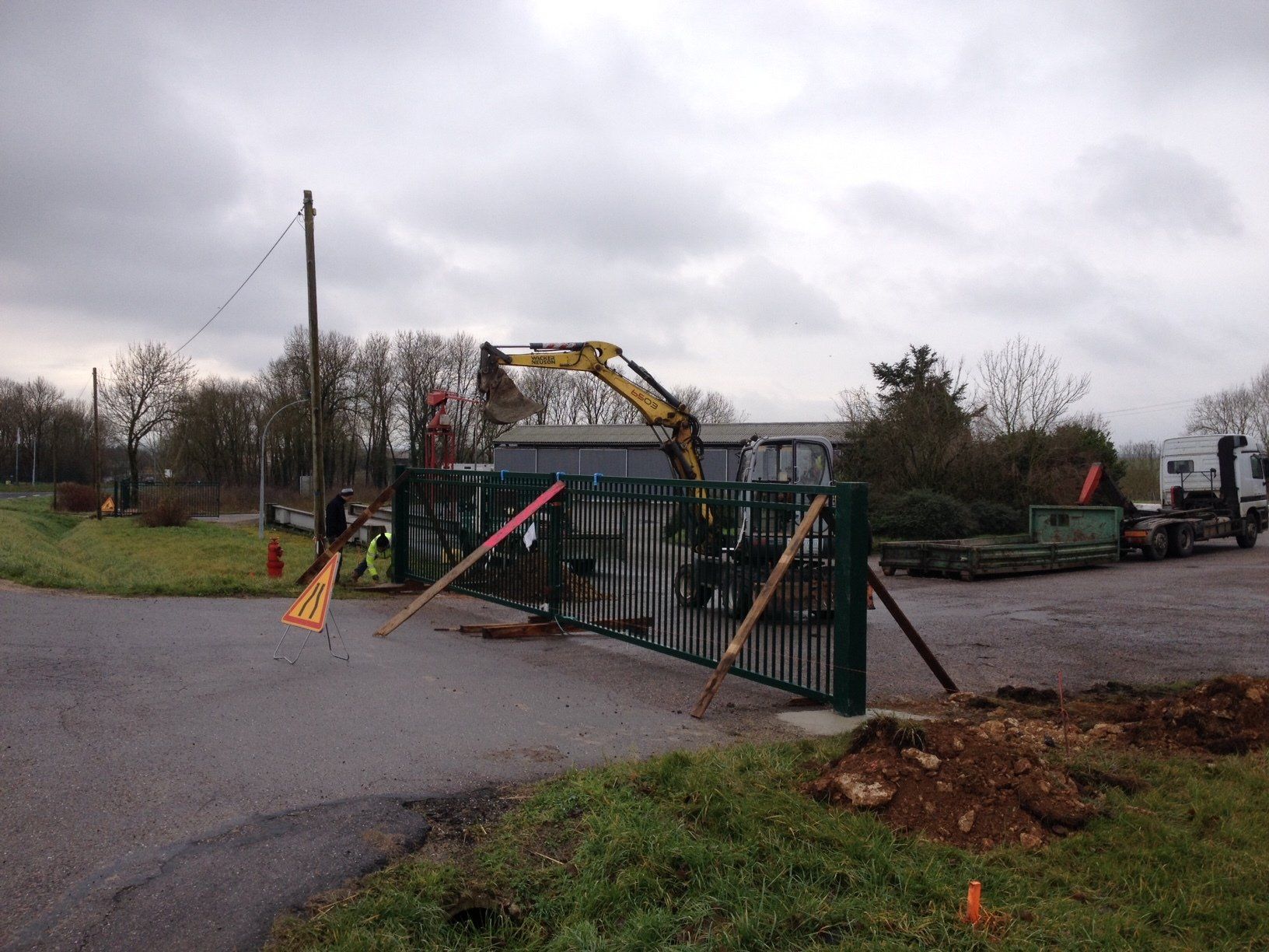 Un chantier avec une barrière et une mini-pelle