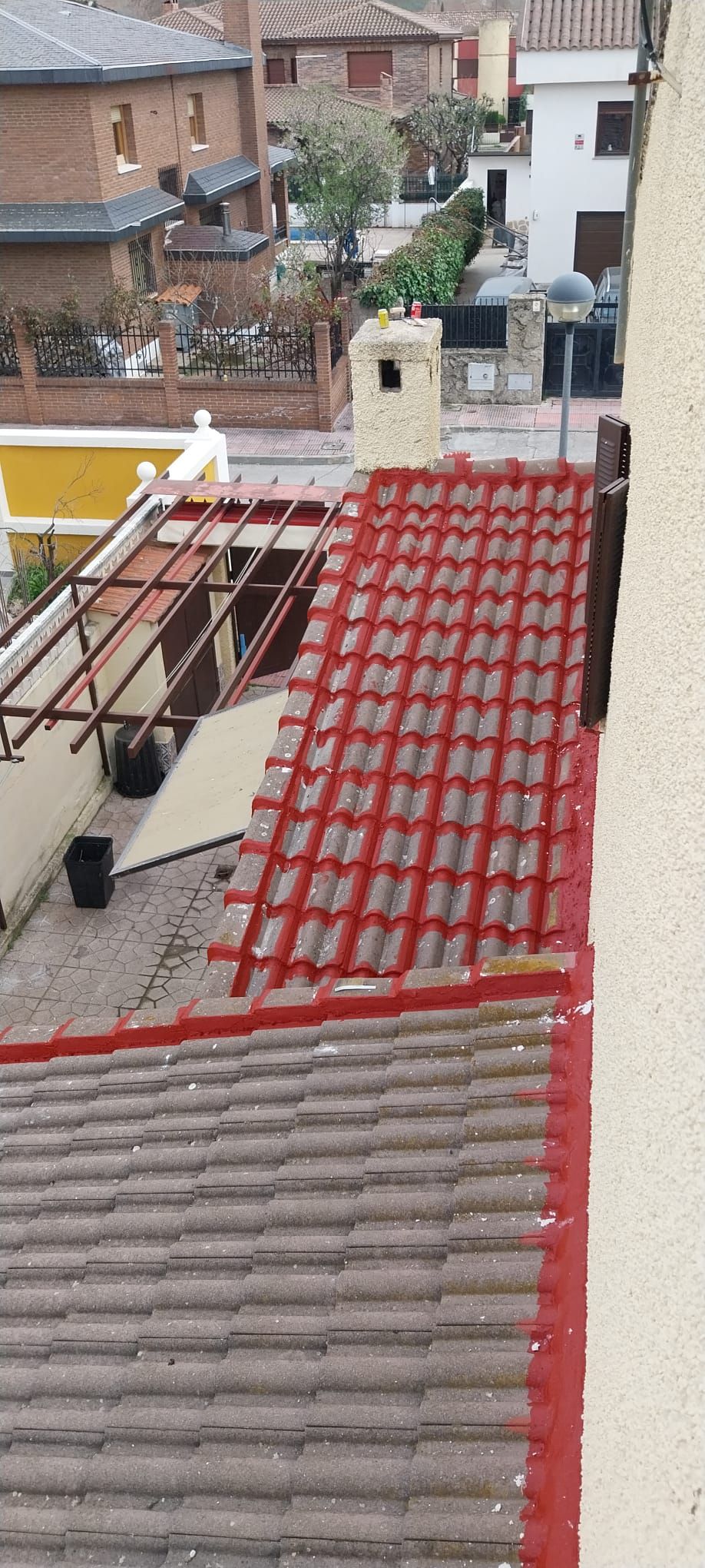 Vista desde una azotea sobre las casas vecinas y una calle estrecha, con tejados de tejas rojas y grises en primer plano.
