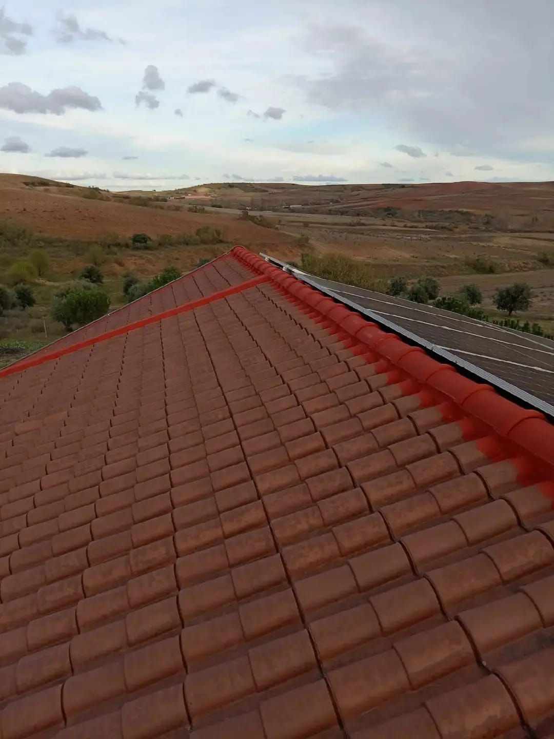 Azotea de tejas rojas con vistas a un vasto paisaje árido bajo un cielo nublado.