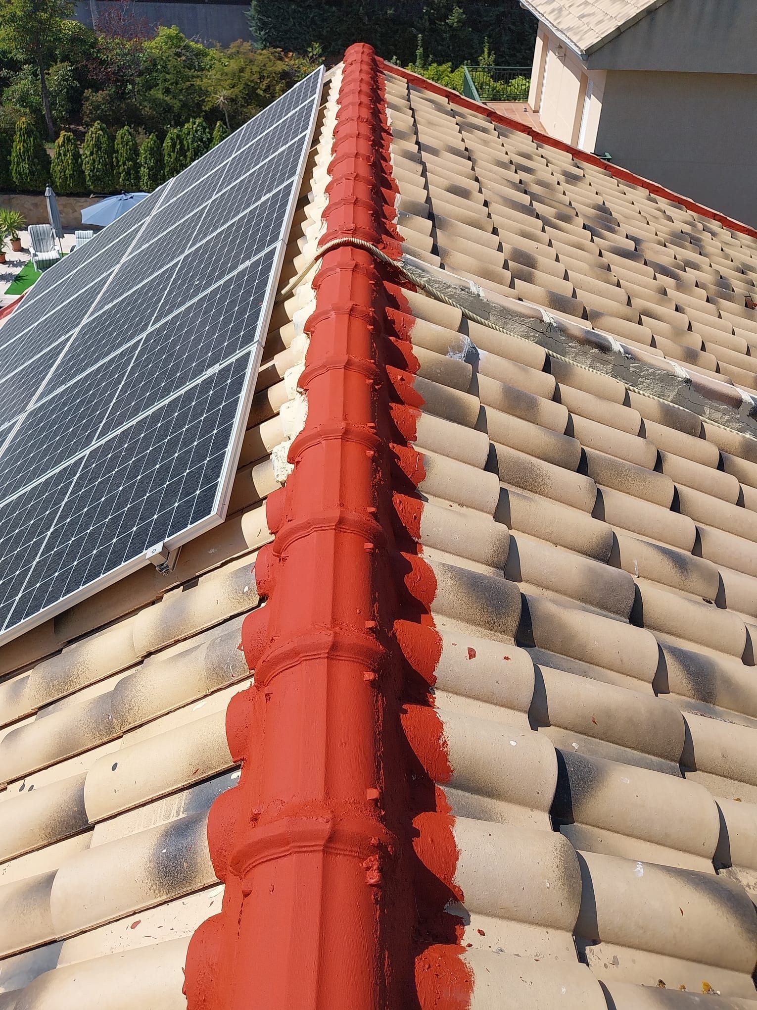 Paneles solares instalados a lo largo de una cresta roja en un tejado de tejas.