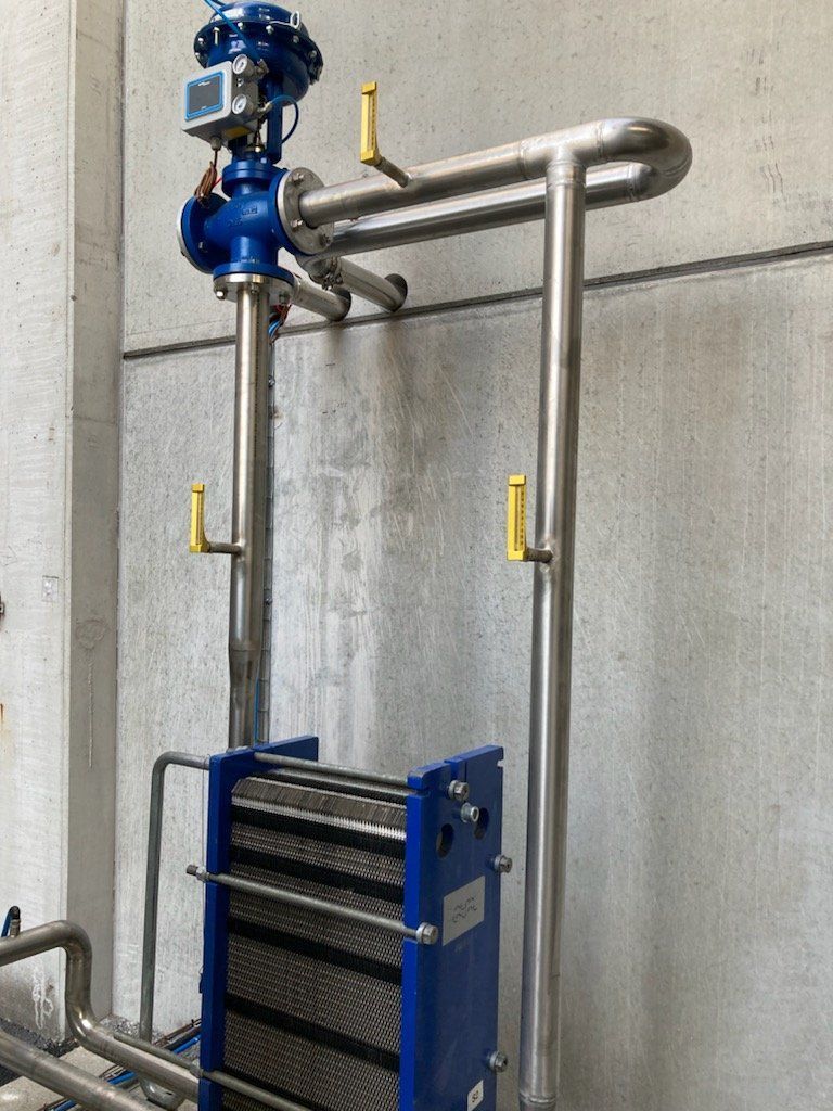 Salon lumineux et moderne avec des murs blancs, un canapé bleu canard, une télévision fixée au mur et des rideaux voilages