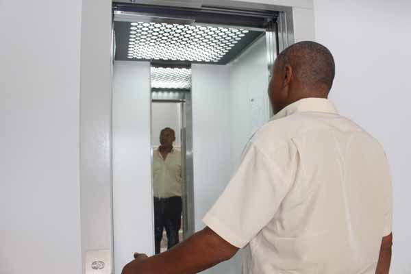 Homem prestes a entrar no elevador. O interior do elevador é reflexivo.