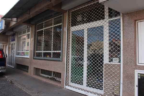 Vista exterior de um edifício comercial com grades de segurança sobre as janelas e portas.