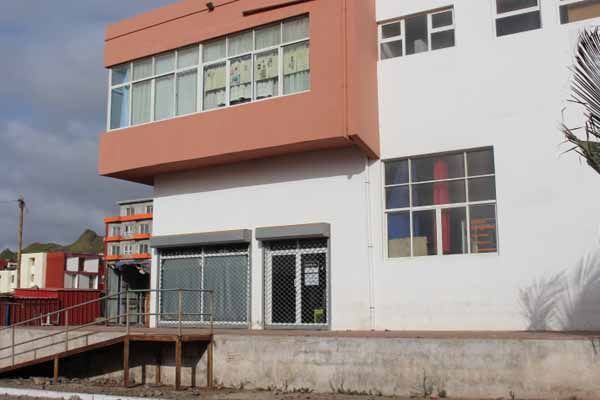 Prédio com fachada branca e laranja, persianas de enrolar e rampa.