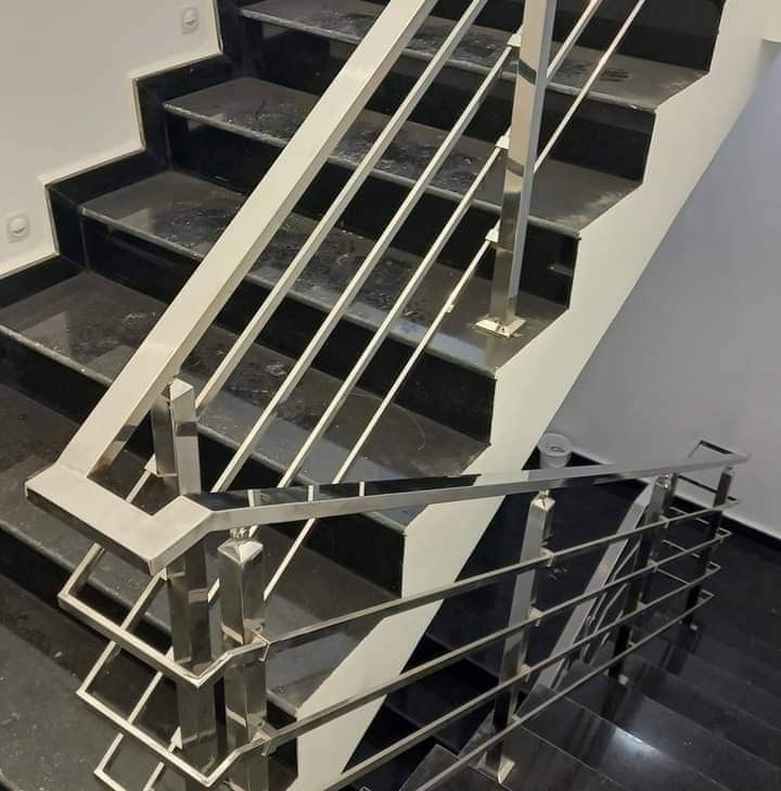 Escadaria com degraus de mármore preto e corrimão de metal.