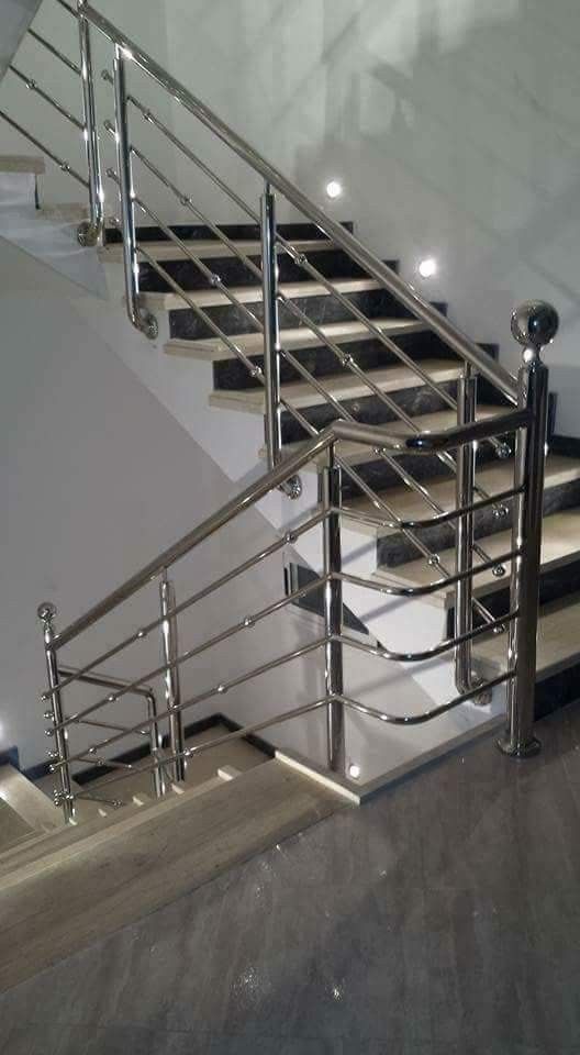 Escada em aço inoxidável com corrimãos, degraus e design em padrão quadriculado. Ambiente interno, arquitetura moderna.