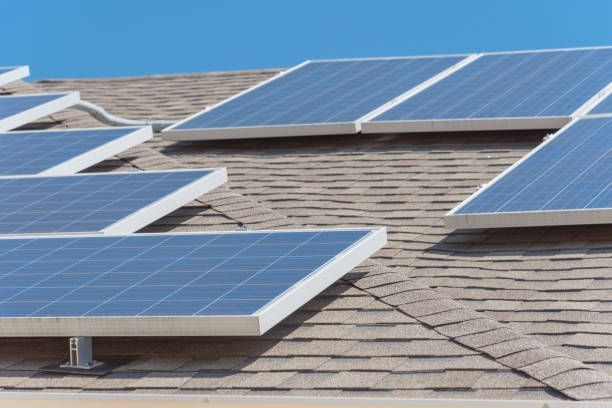 Painéis solares instalados em um telhado de telhas marrons, contra um céu azul.