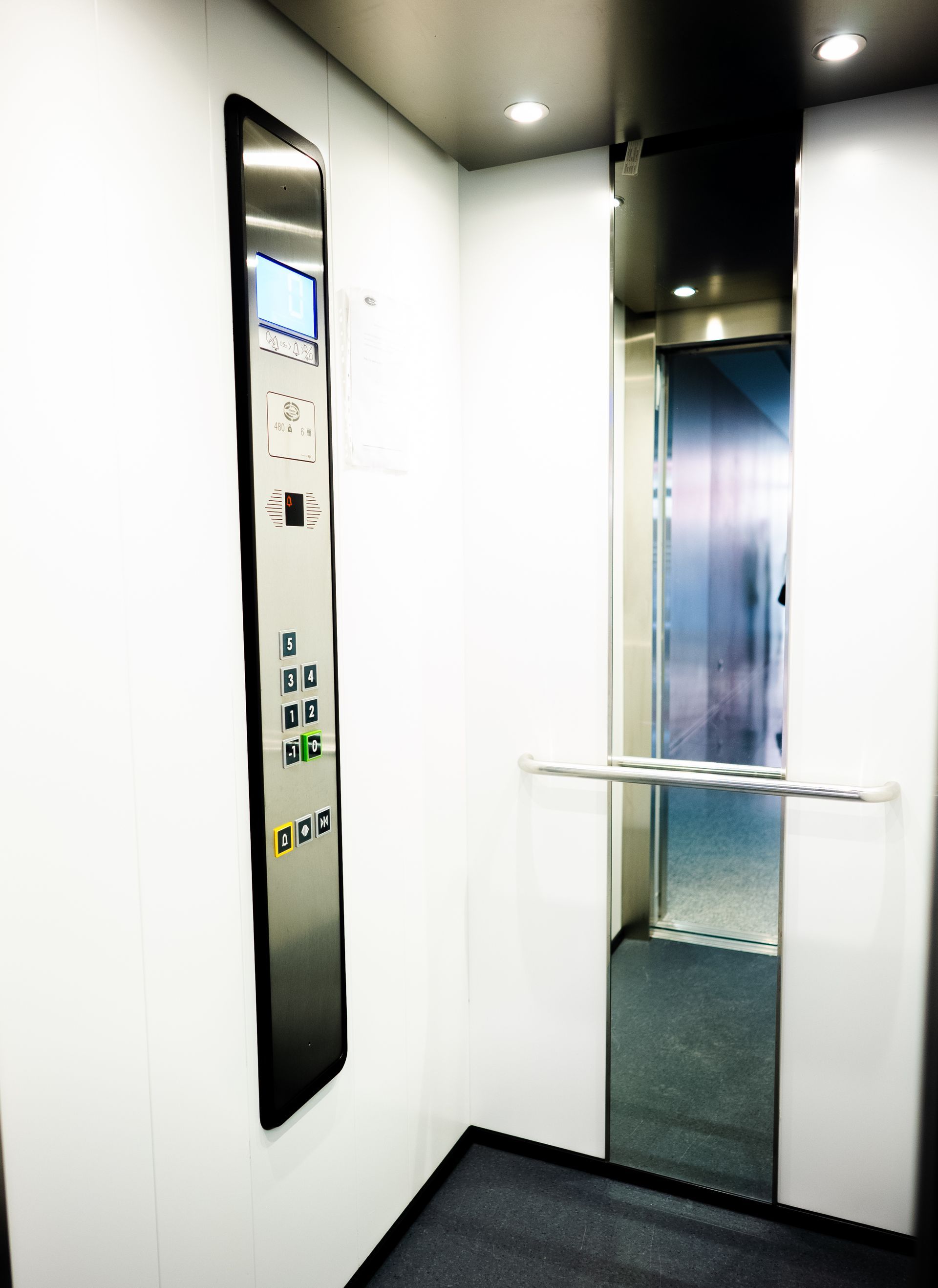 Interior de um elevador com painel de controle e porta aberta.