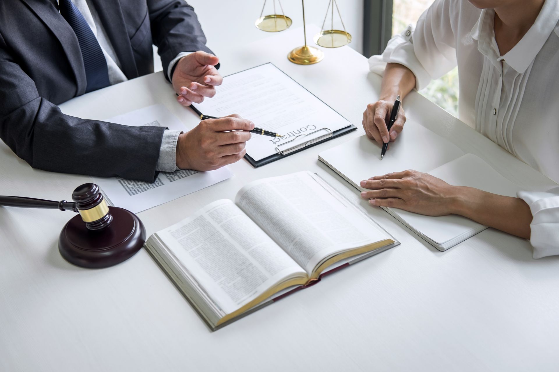Des avocats examinent des documents autour d'une table. Sur la table sont posés une balance et un maillet.
