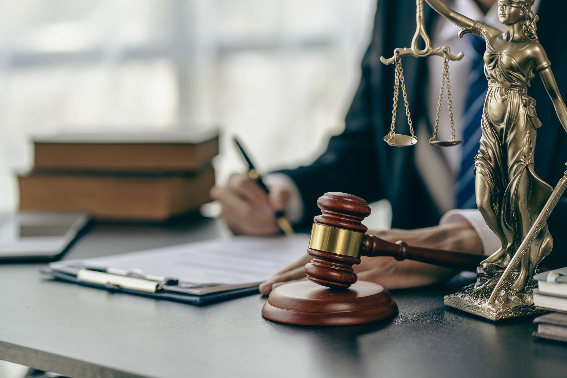 Un bureau d'avocat avec une balance de la justice et une personne écrivant en arrière-plan.