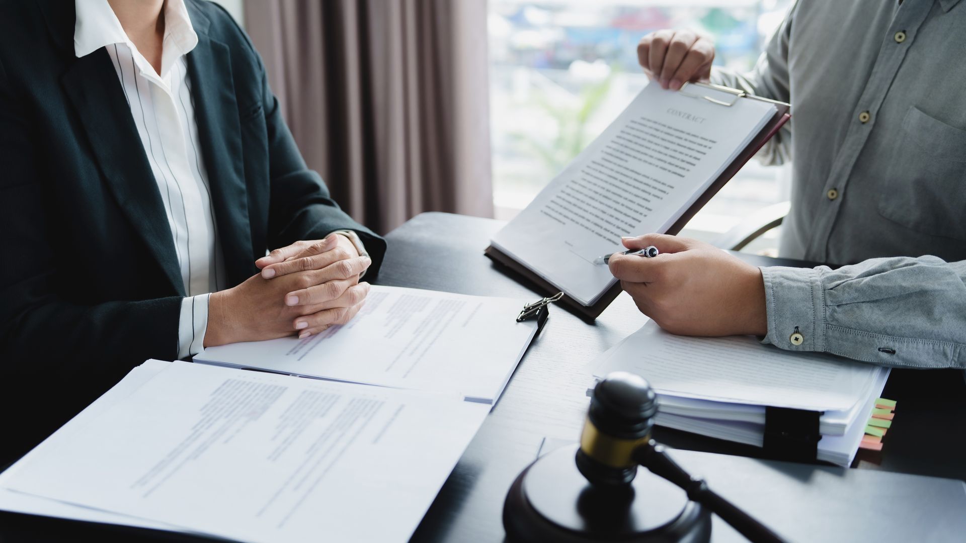 Deux personnes examinent un contrat à un bureau avec un maillet au premier plan.