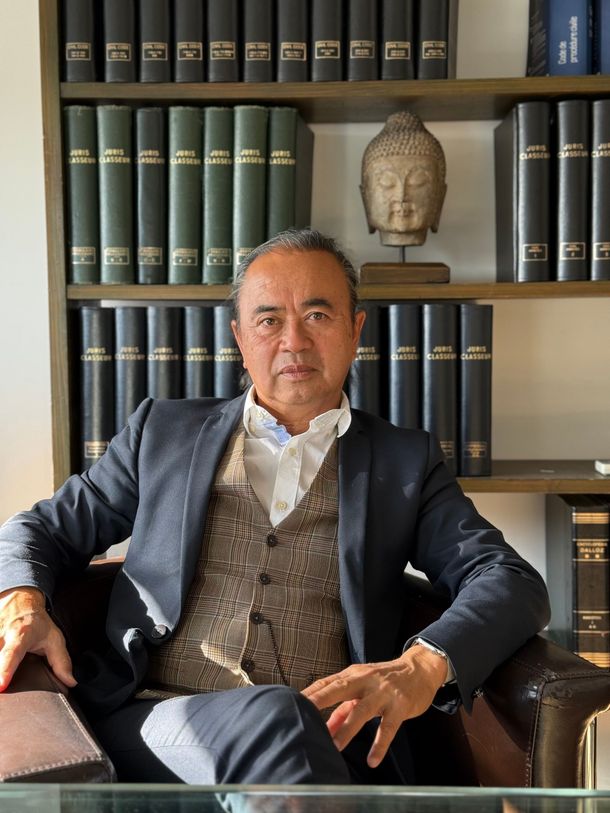 Maître NGUYEN devant la bibliothèque de son bureau.
