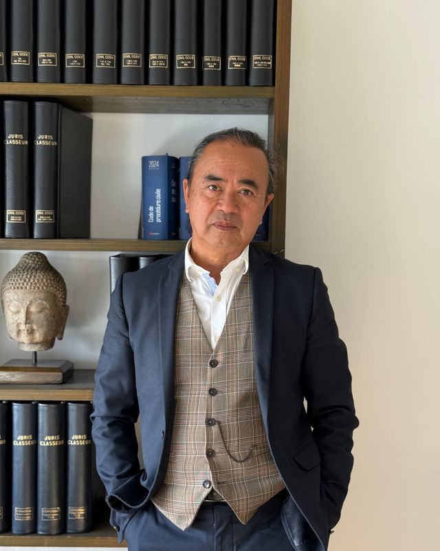 Une photo de Maître NGUYEN devant la bibliothèque de son bureau.