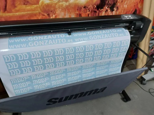 Impresora de gran formato alimentando un rollo de material impreso de color azul claro con el logotipo