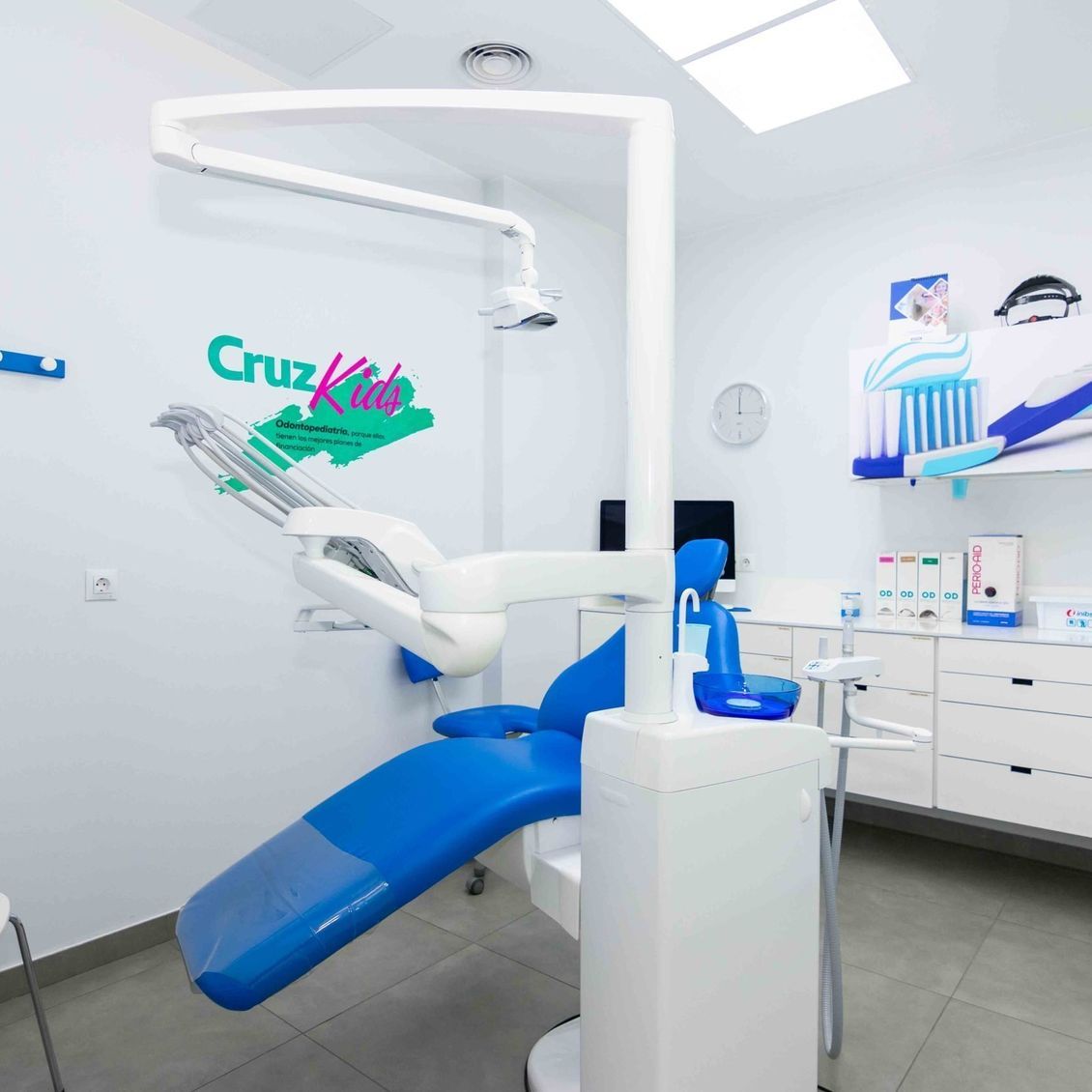 Una silla dental azul en un consultorio dental con la palabra Cruz Kids en la pared.