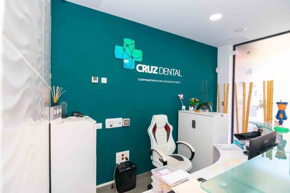Un consultorio dental con una pared azul y una silla blanca.