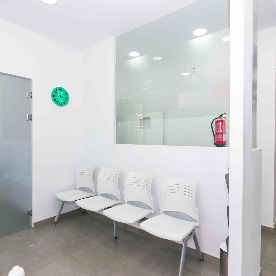 Una sala de espera con sillas y un reloj en la pared.