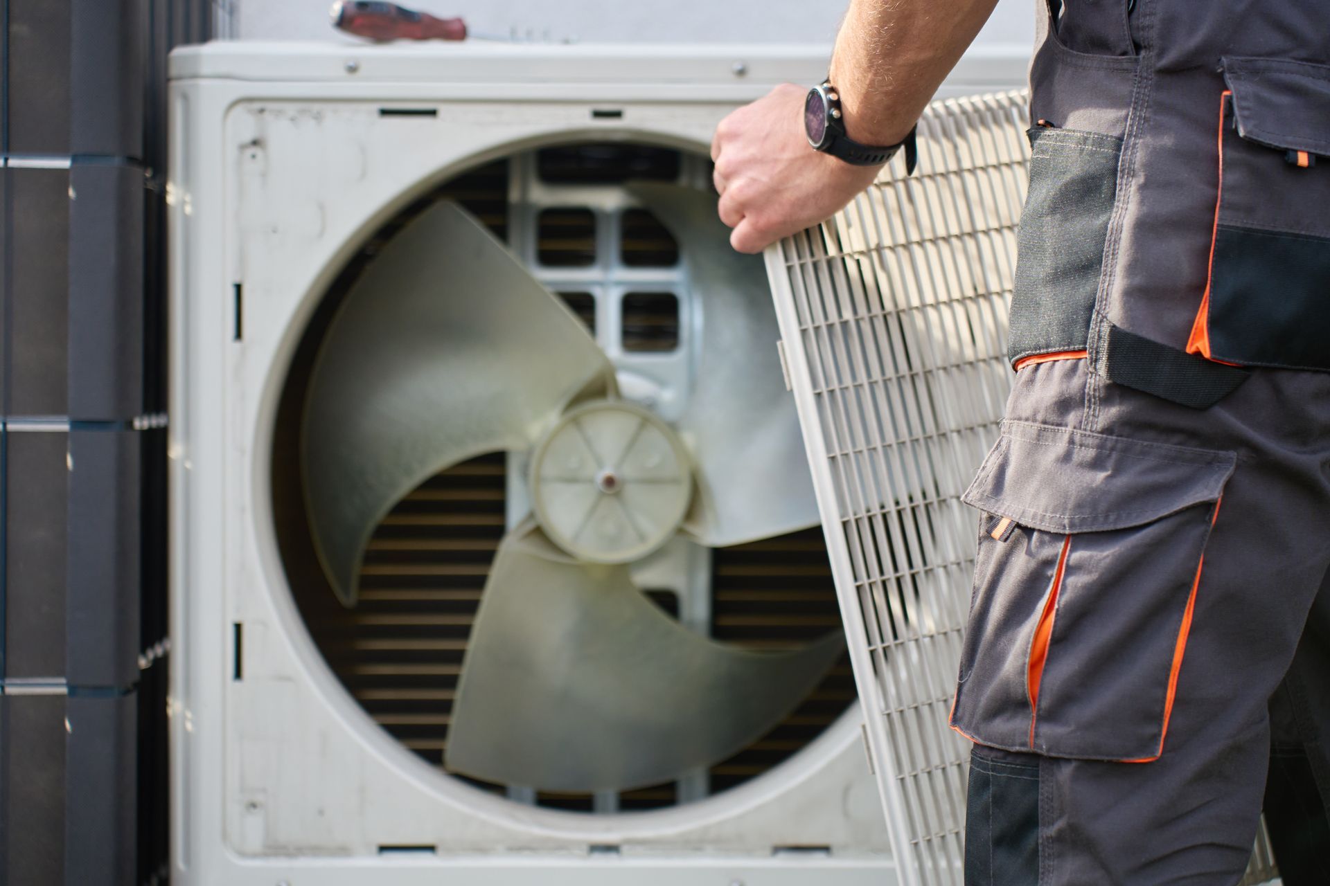 Un technicien inspecte une unité de climatisation extérieure dont le panneau avant a été retiré.