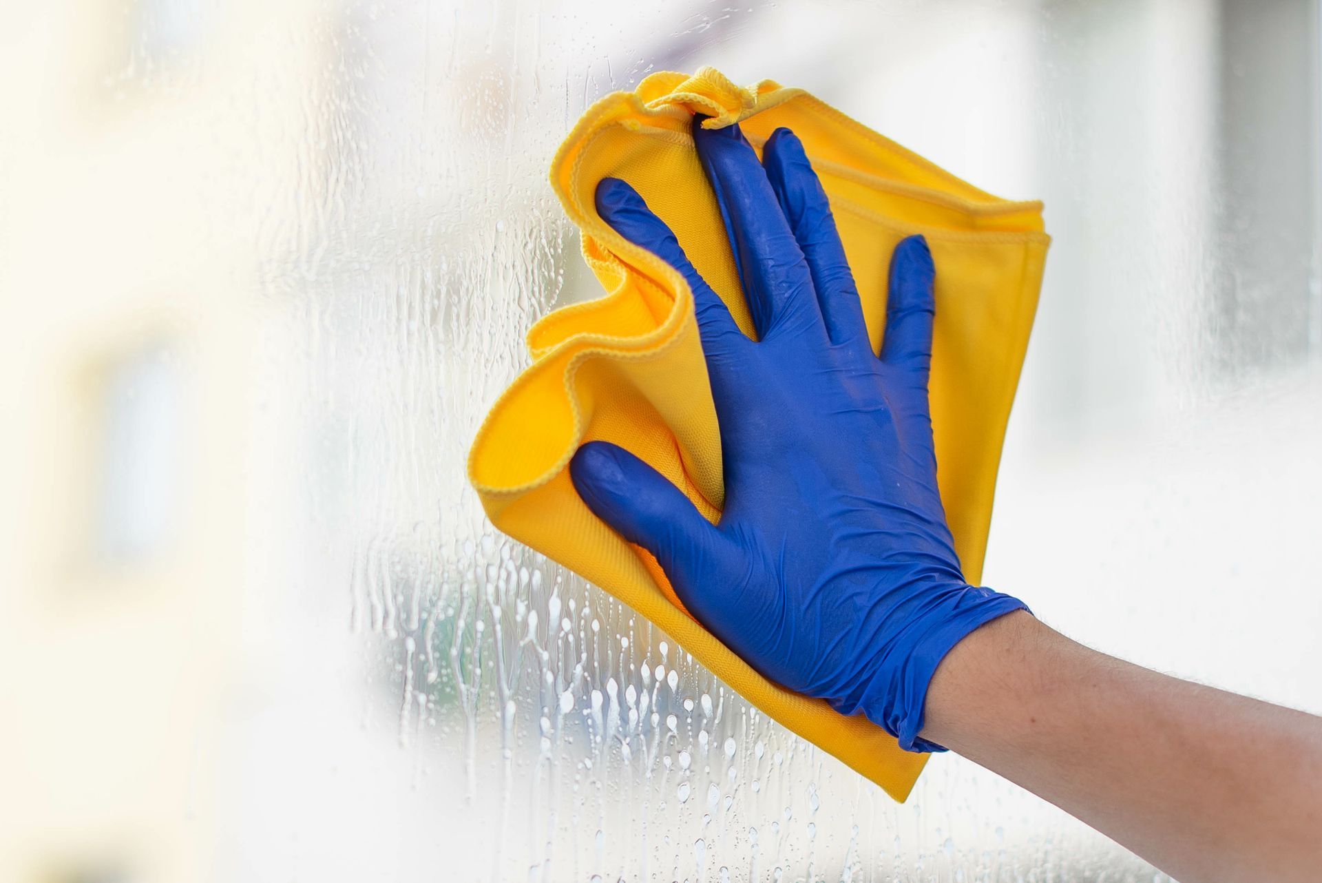 Nettoyage de vitre avec un chiffon jaune.