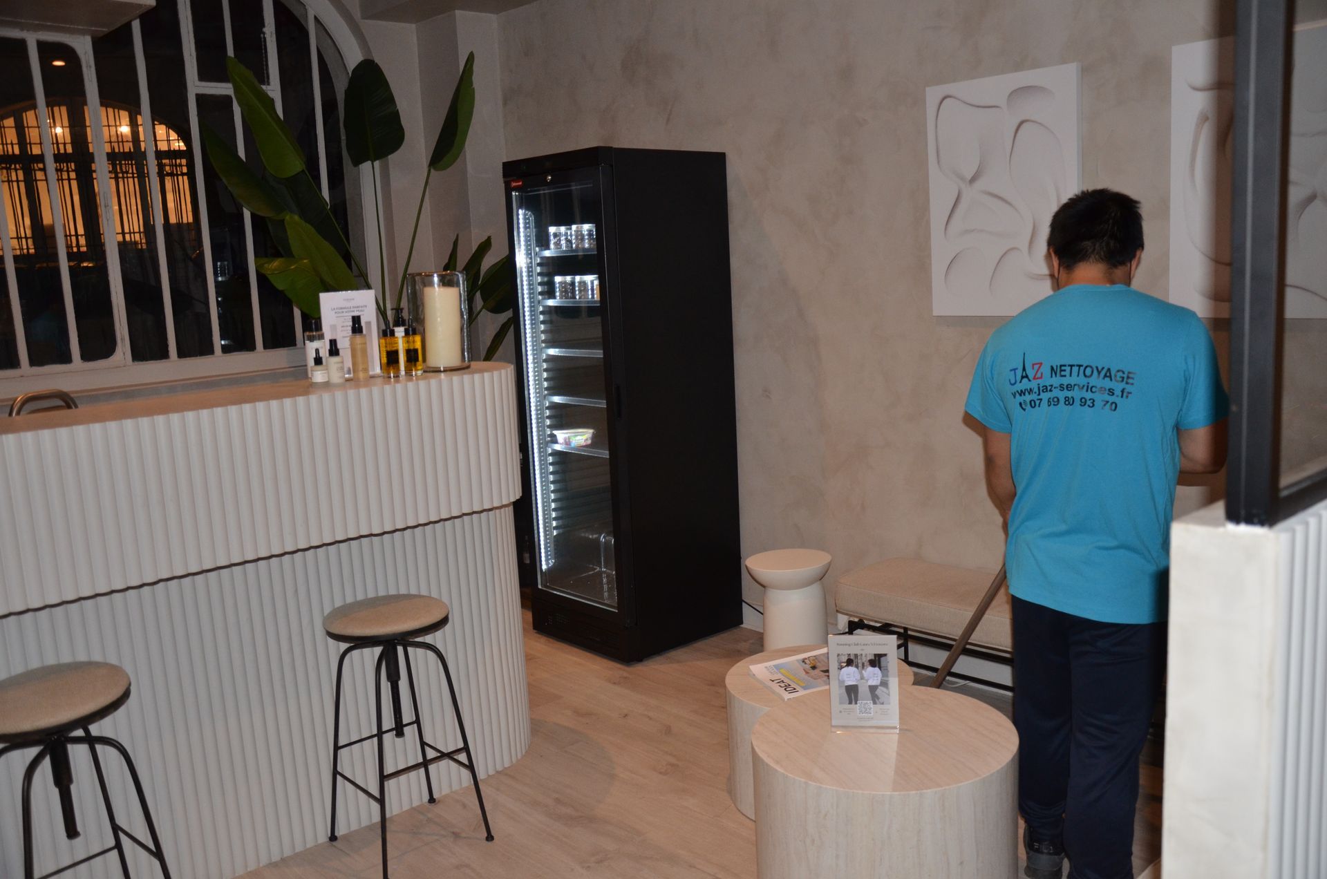 Homme qui passe le balai dans l'accueil d'un magasin.