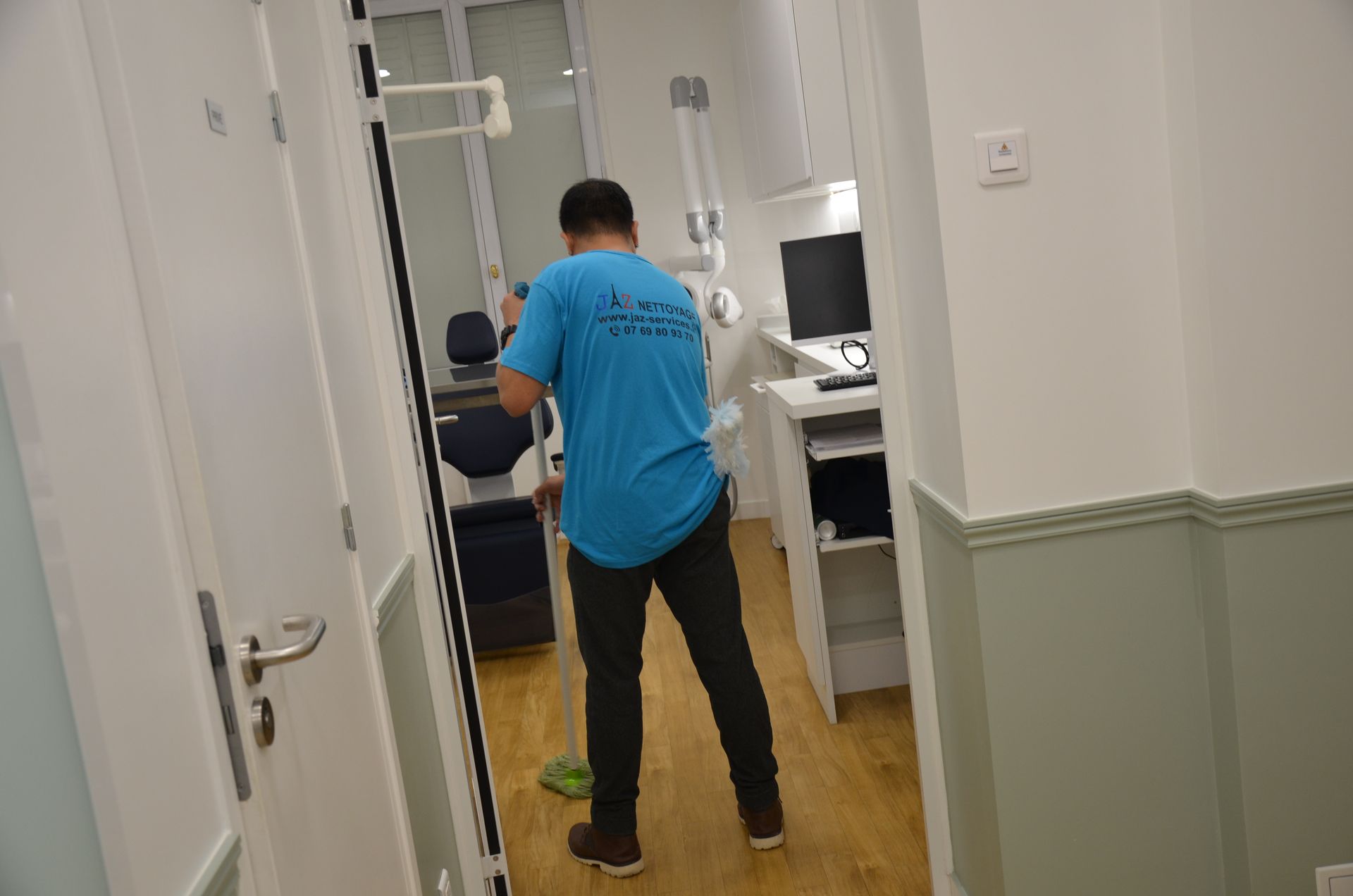 Homme qui passe la serpillière sur le sol d'un cabinet dentaire.