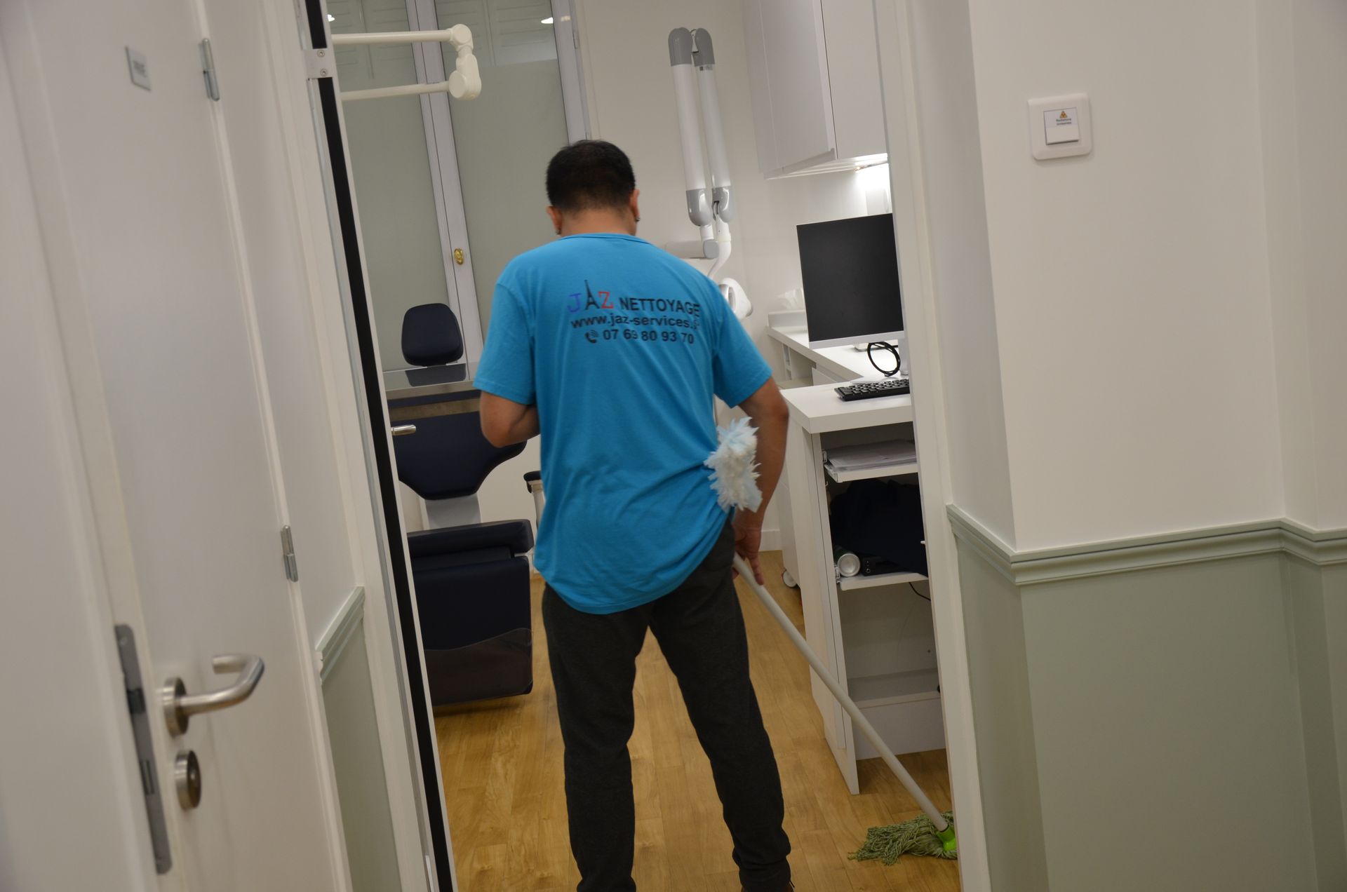 Homme qui passe le balai dans le cabinet d'un dentiste.