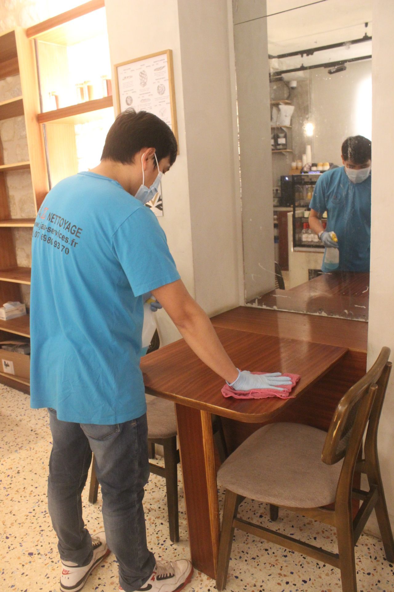 Homme qui nettoie une table de restaurant.
