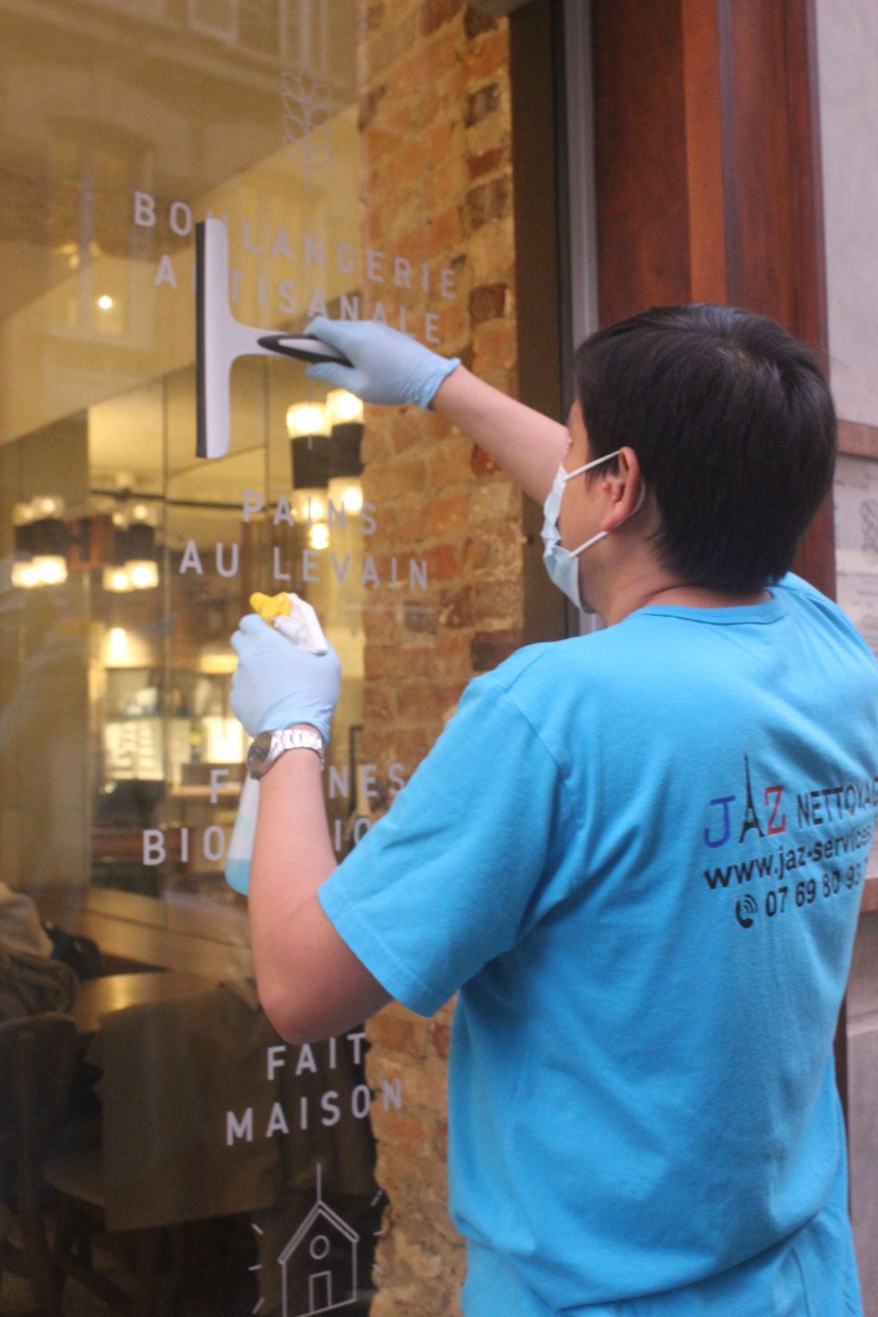 Homme qui nettoie des vitres avec une raclette.