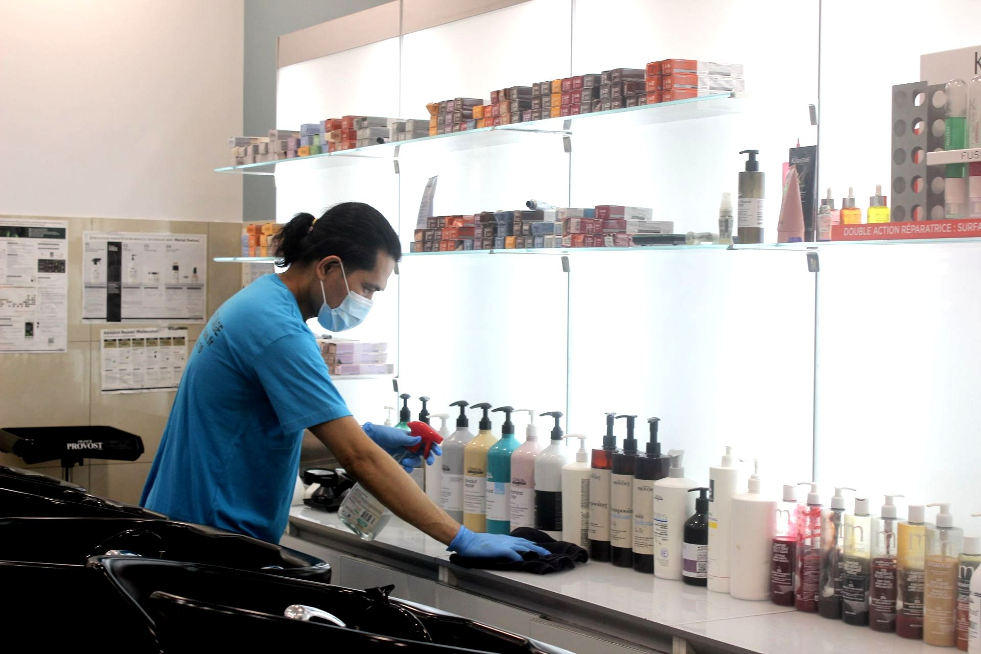 Homme qui nettoie le plan de travail d'un coiffeur.