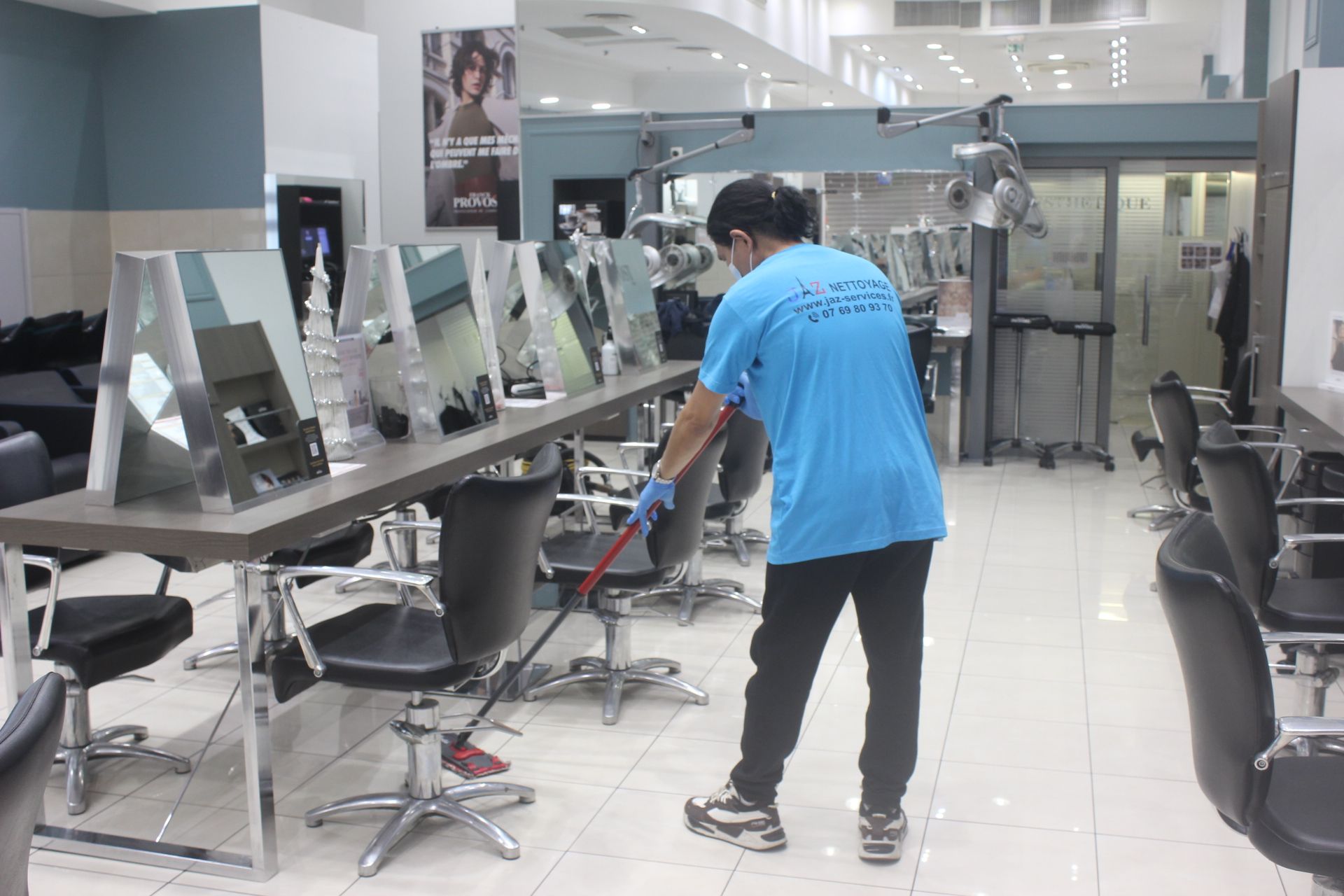 Homme qui passe la serpillière dans un salon de coiffure.