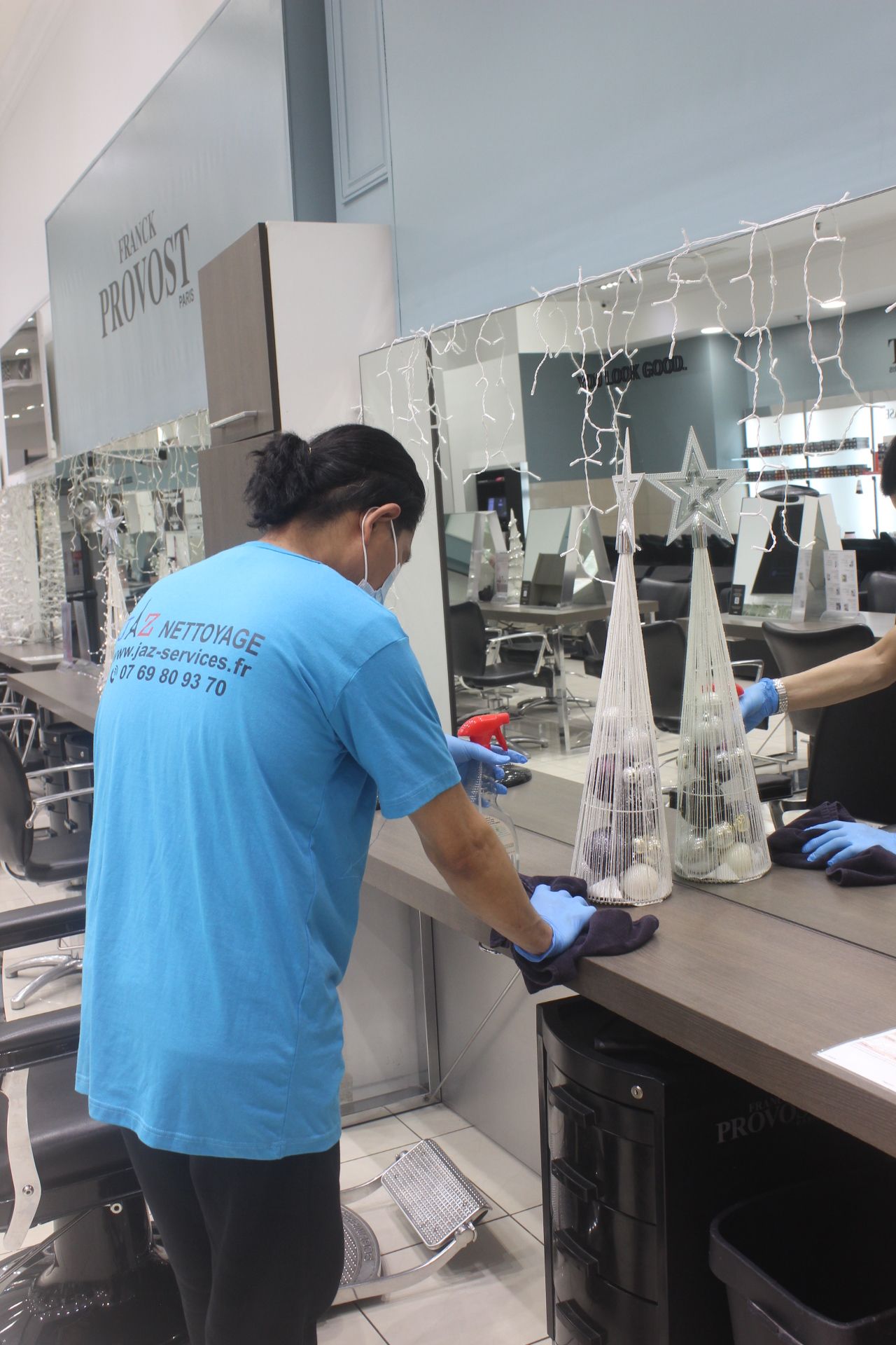 Homme qui nettoie le miroir d'un salon de coiffure.