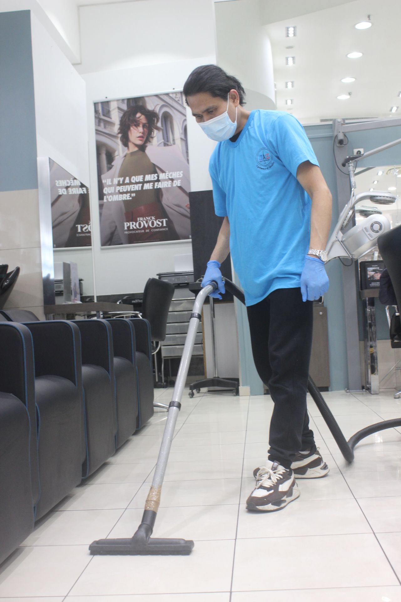 Homme qui passe l'aspirateur dans un salon de coiffure.