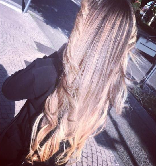 Femme aux longs cheveux blonds ondulés ; à l'extérieur, au soleil.