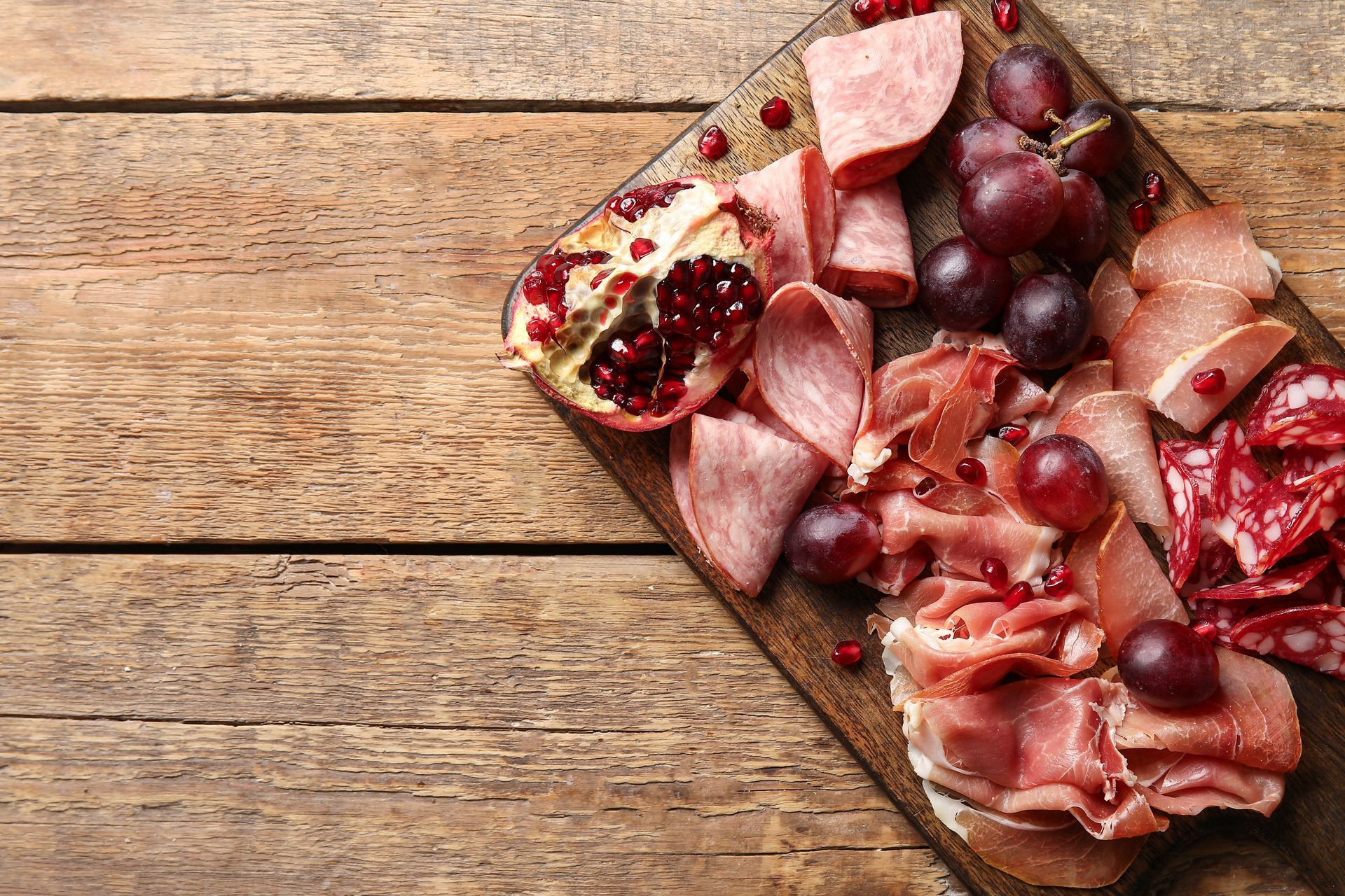 Wurstplatte: Käse, Fleisch, Brot, Oliven, Essiggurken und Wein auf Holzbrettern.