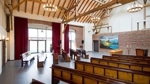 Eine Kirche mit Holzbänken und einem Gemälde an der Wand.