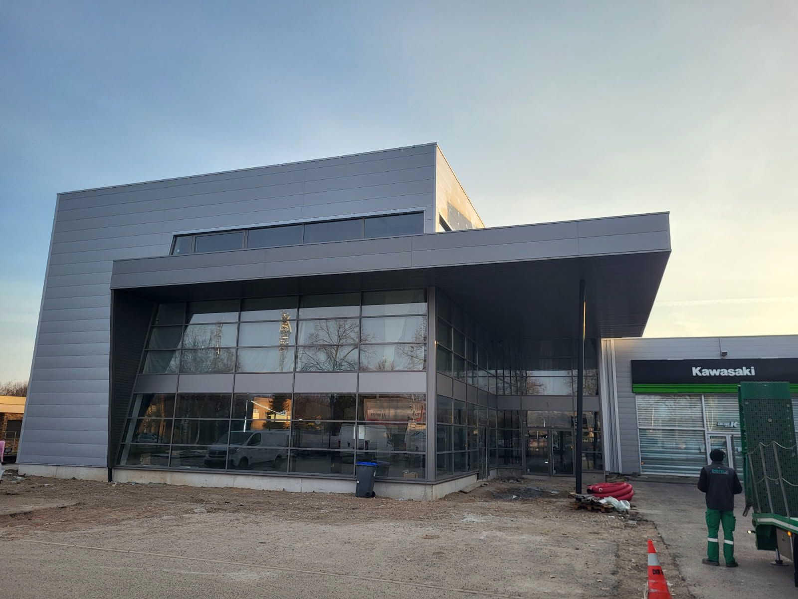 Bâtiment moderne d'une concession Kawasaki avec de grandes baies vitrées et une entrée couverte.
